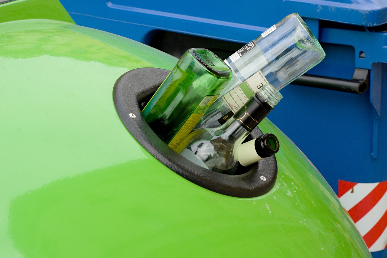 Botellas asomando de un contenedor de reciclaje de vidrio. Imagen de dominio público