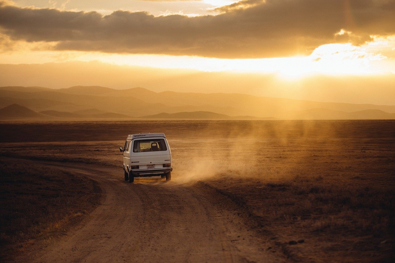 Fotografía de una Volkswagen alejándose por un camino de tierra