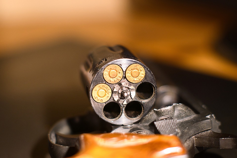 Tambor de un revólver abierto mostrando 3 balas en sus 6 orificios