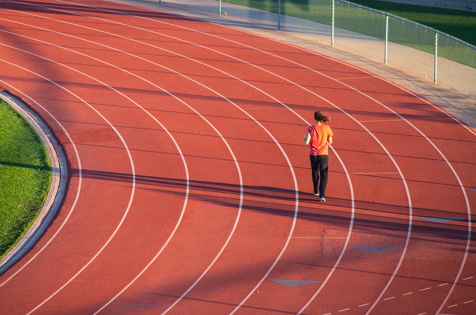 Mujer corriendo en la curva de una pista de atletismo