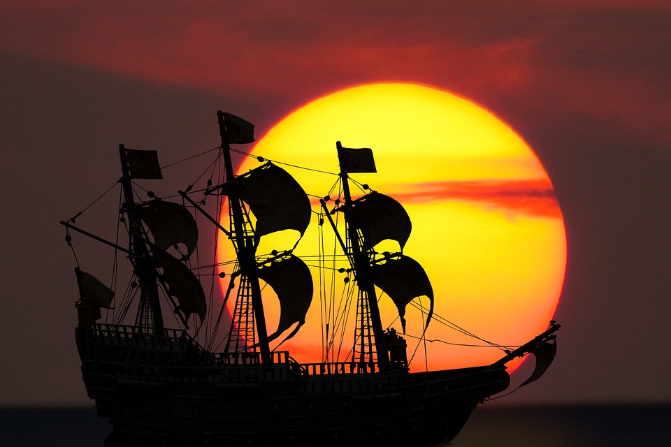 Barco pirata en el horizonte delante de una puesta de sol