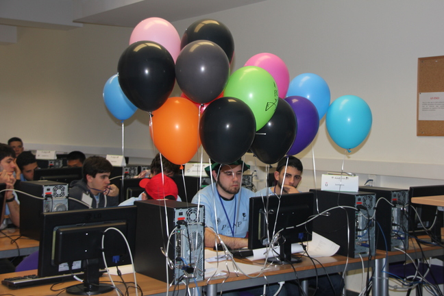 Un equipo durante un concurso de programación con globos representando problemas resueltos