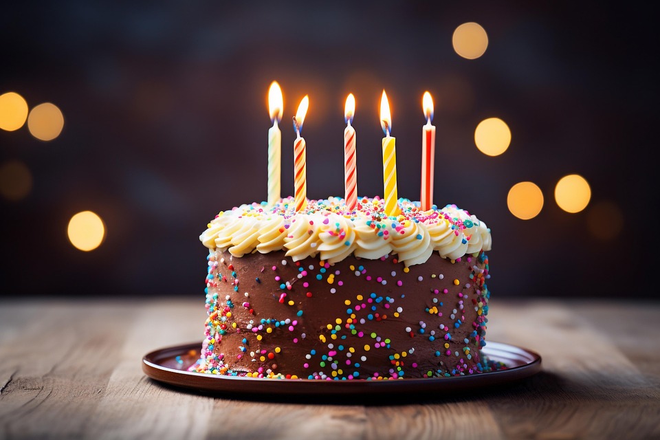 Tarta de chocolate peque&ntilde;a con 5 velas encendidas encima